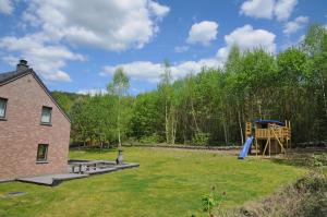 un patio con parque infantil y una casa en Villa Noach, en Durbuy