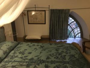 a bedroom with a bed with a green bedspread and a window at Castello Sannazzaro B&B in Giarole