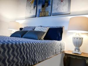 Una cama con almohadas azules y una lámpara en una mesa. en Privilege Menorca Apartment en Mahón