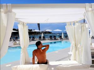 a man sitting on a balcony overlooking the ocean at AxelBeach Ibiza Suites Apartments Spa and Beach Club - Adults Only in San Antonio Bay