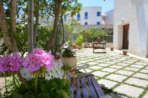 une terrasse avec 2 bancs et des fleurs roses dans l'établissement Guest House Al Giardino dei Limoni, à Favignana