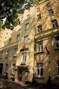 um edifício com uma bandeira vermelha à sua frente em Primo Hotel em Riga