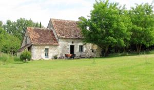 uma velha casa de pedra num campo com uma árvore em Gite La Bergerie em Varennes