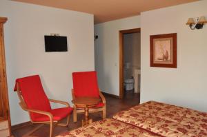a bedroom with a bed and two chairs and a tv at Hotel Langa in Cerezo de Abajo