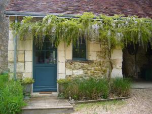 VarennesにあるLe four à painの青い扉とブドウの木がある石造りの家