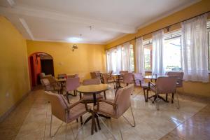 uma sala de jantar com mesas, cadeiras e janelas em Jinja Safari Hotel em Jinja