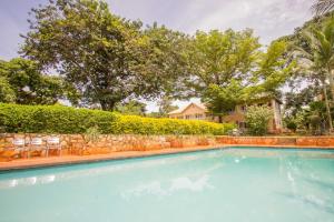 a swimming pool in front of a house with trees at Jinja Safari Hotel in Jinja