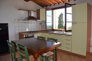 cocina con mesa de madera y sillas verdes en Appartamento Belvedere, en Guardistallo