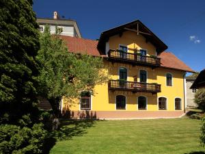 a yellow house with a balcony on top of a yard at Pension Alte Mühle in Gmünd in Kärnten