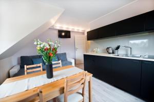 a kitchen and a living room with a table and a couch at Dom Gościnny Agawa in Niechorze