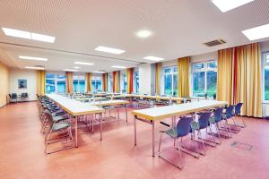 a large room with tables and chairs and windows at Jugendherberge Jever in Jever