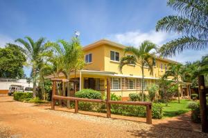 a yellow house with palm trees in front of it at 2 Friends Guest House in Jinja