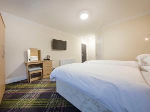 a bedroom with two beds and a desk with a television at The Bay Horse in Hamilton