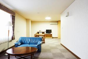 a living room with a blue couch and a table at Nasushiobara Station Hotel in Nasushiobara