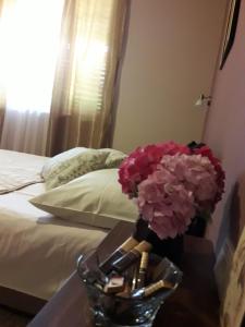 a vase of flowers on a table next to a bed at Apartments Ant in Budva