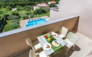a balcony with a table and chairs with food on it at Apartments Viktorija in Baška