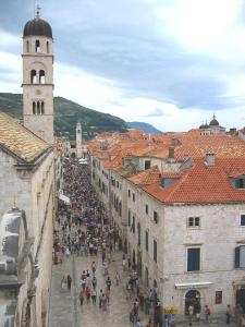 una multitud de personas caminando alrededor de una ciudad con una torre de reloj en Kuća Cvjetković, en Gruda