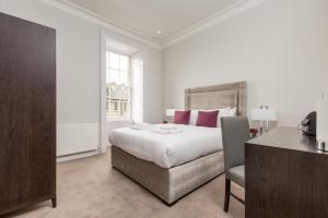 um quarto branco com uma cama, uma secretária e uma cadeira em Destiny Scotland - Chisholm Hunter Suites em Edinburgo