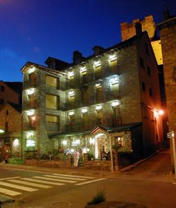 un grand bâtiment avec des lumières sur le côté d'une rue dans l'établissement Apartamentos Gabarre, à Broto