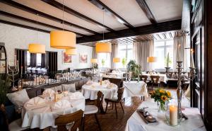 a restaurant with white tables and chairs and lights at Amtsstüble Hotel & Restaurant in Mosbach