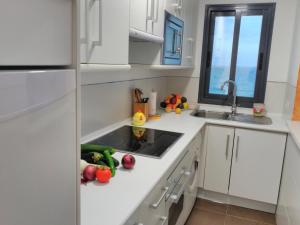 a kitchen with white cabinets and a sink with vegetables on the counter at Camarote in El Morche