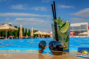 a drink and sunglasses on a table next to a pool at Hotel Alinalex - Paradisul Acvatic in Braşov