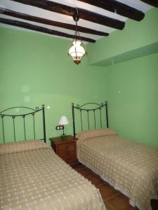 two beds in a room with green walls at Casa rural L'Hospital in Vistabella del Maestrazgo