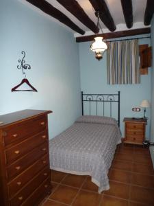- une chambre avec un lit et une commode dans l'établissement Casa rural L'Hospital, à Vistabella del Maestrat