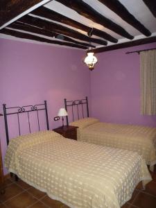 two beds in a room with purple walls at Casa rural L'Hospital in Vistabella del Maestrazgo