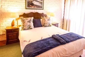 a bedroom with a bed with a blue blanket on it at Swallows Nest Country Cottages in Stormsrivier