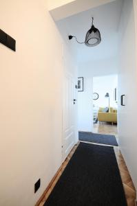 a hallway with white walls and a black rug at A Place Like Home Apartamenty Witosa in Gdańsk