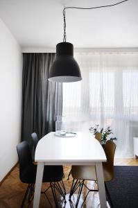 a blackendant light hanging over a white dining room table at A Place Like Home Apartamenty Witosa in Gdańsk