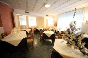 een eetkamer met tafels en stoelen met bloemen erop bij Hotel Italia in Aprica