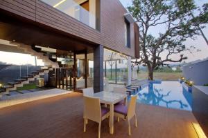 a patio with a table and chairs next to a pool at Luxury Goa Villa in Candolim