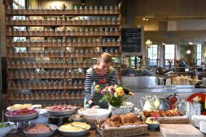 a woman standing behind a counter with a table of food at Villa Augustus in Dordrecht