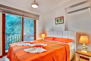 a bedroom with a bed with orange sheets and a window at Kasinn Apart Turuncu in Kaş