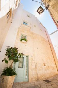 a white building with a door and a plant at Trame - La Naca sul Porto in Polignano a Mare