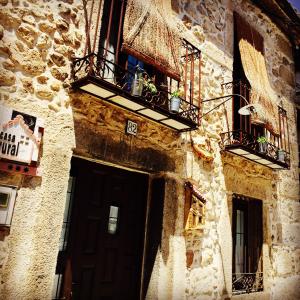 - un bâtiment en pierre avec une porte et un balcon dans l'établissement Las Cuatro Calles, à Piedralaves