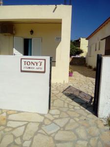 a white house with a sign on the side of it at Tony's Apartments in Agios Georgios