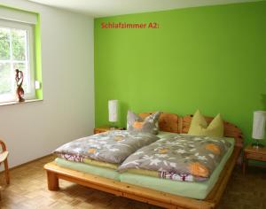 a bed in a room with a green wall at Ferienwohnungen 99a in Weimar