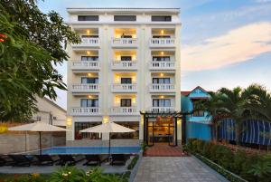 a white hotel with umbrellas in front of it at Viet Long Hoian Beach Hotel - STAY 24H in Hoi An