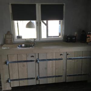 a kitchen counter with a sink and two windows at Hof van donzel in Nistelrode