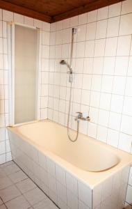 W wyłożonej kafelkami łazience znajduje się wanna z prysznicem. w obiekcie Work & Stay in Zuelpich w mieście Zülpich