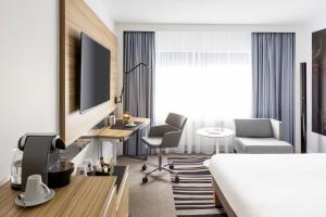 a hotel room with a bed, desk, chair and a television at Novotel Amsterdam City in Amsterdam