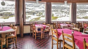 un restaurante con mesas y sillas con montañas cubiertas de nieve en Hotel Restaurant Monte Leone, en Simplon Dorf