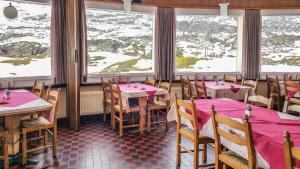 ein Restaurant mit Tischen und Stühlen und schneebedeckten Bergen in der Unterkunft Hotel Restaurant Monte Leone in Simplon Dorf