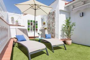 two chairs and an umbrella on a balcony with grass at Fantastic Penthouse Malaga Center in Málaga