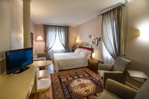Schlafzimmer mit einem Bett und einem Schreibtisch mit einem TV in der Unterkunft Regina Adelaide Hotel & SPA in Garda