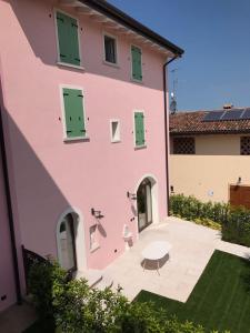 un edificio rosa con puertas verdes y una mesa en Casa Bardalla, en Ponti Sul Mincio