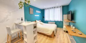 - une chambre avec des murs bleus, un lit et un bureau dans l'établissement Les Quais d'Annecy, à Annecy
